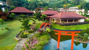 A traditional Japanese garden with a torii gate, a stone pathway, and a pond.