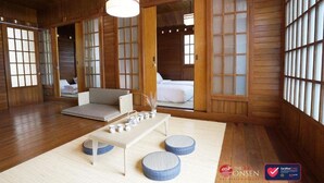 A traditional Japanese-style room with tatami flooring, a low table with cushions, and sliding doors with glass panels.