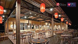 An outdoor dining area with wooden tables and chairs, red lanterns, and a covered roof.