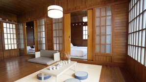 Ein traditioneller japanischer Raum mit Tatami-Bodenbelag, einem niedrigen Tisch mit Kissen und verschiebbaren Glastüren.