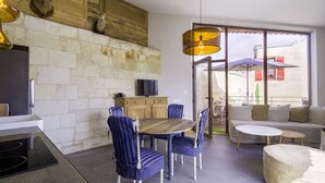 Eine moderne Küche mit Steinwand, Holzschränken und einem Essbereich mit blauen Stühlen und einem runden Tisch.