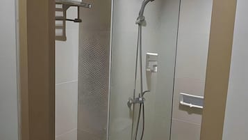 A modern bathroom with a glass partition, a shower with a handheld showerhead, and a toilet.