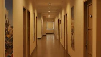 A hotel hallway with doors on both sides, a tiled floor, and recessed lighting.