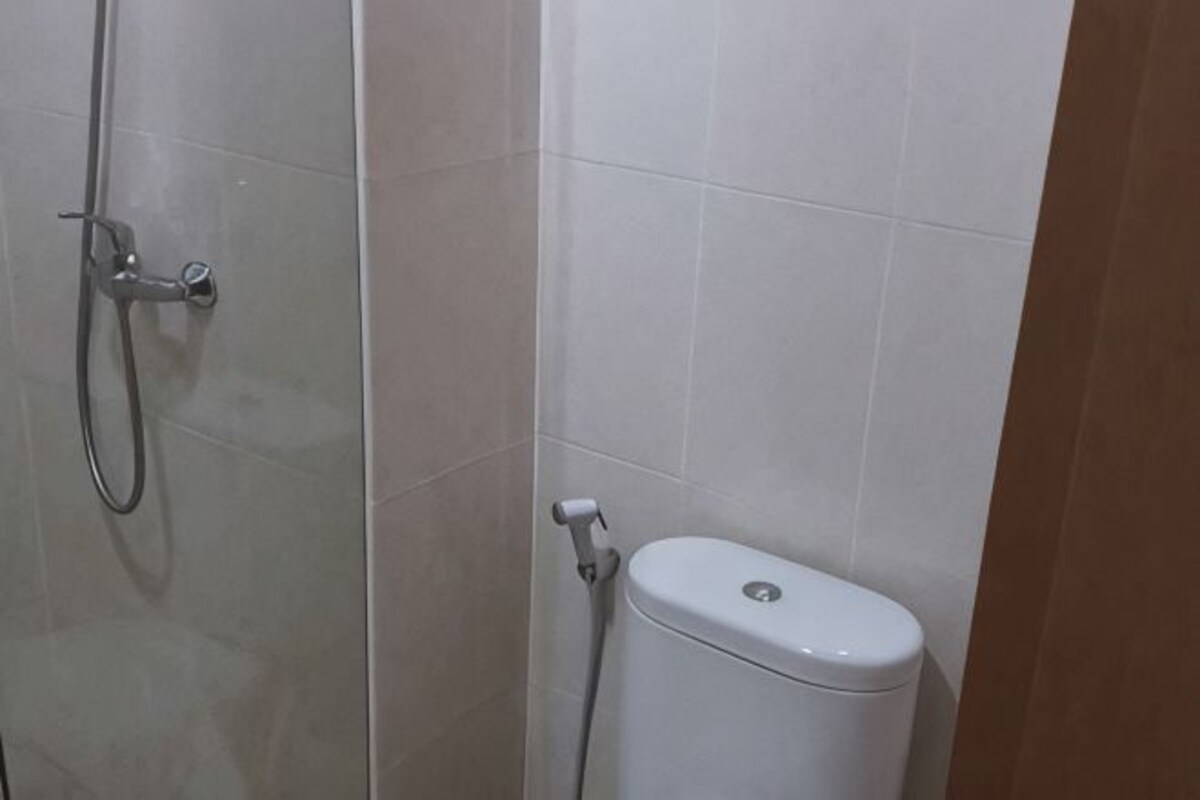 Un baño con ducha, inodoro y paredes de azulejos.