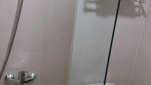 A bathroom with a shower, toilet, and glass partition. - Cordela Hotel Pangkal Pinang (Pangkalpinang)
