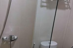 A bathroom with a shower, toilet, and glass partition. - Cordela Hotel Pangkal Pinang (Pangkalpinang)