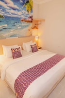 Habitación de hotel con una cama grande, una mesita de noche, una lámpara y un cuadro de playa en la pared.