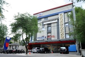 Un hotel con un cartel que indica que es un hotel y un estacionamiento con varios vehículos.