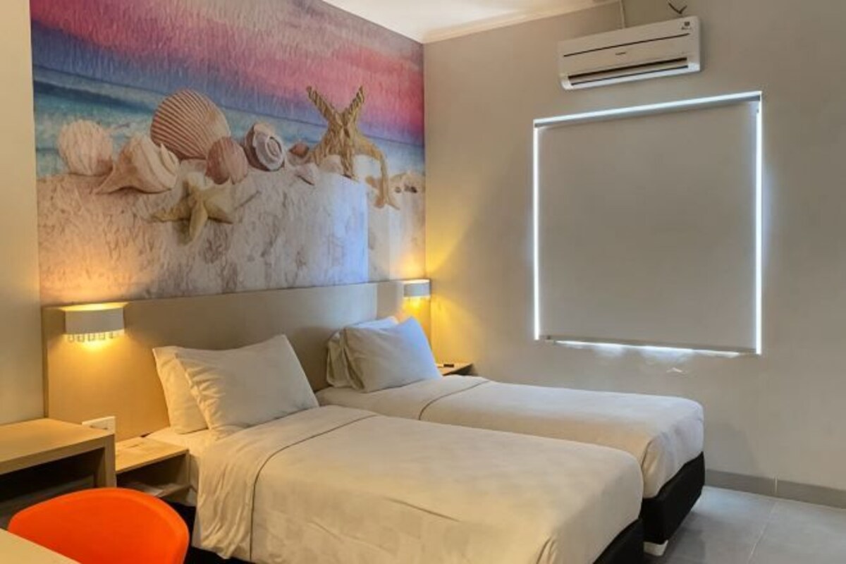 Habitación de hotel con dos camas, un cuadro de criaturas marinas en la pared y un ventanal grande.