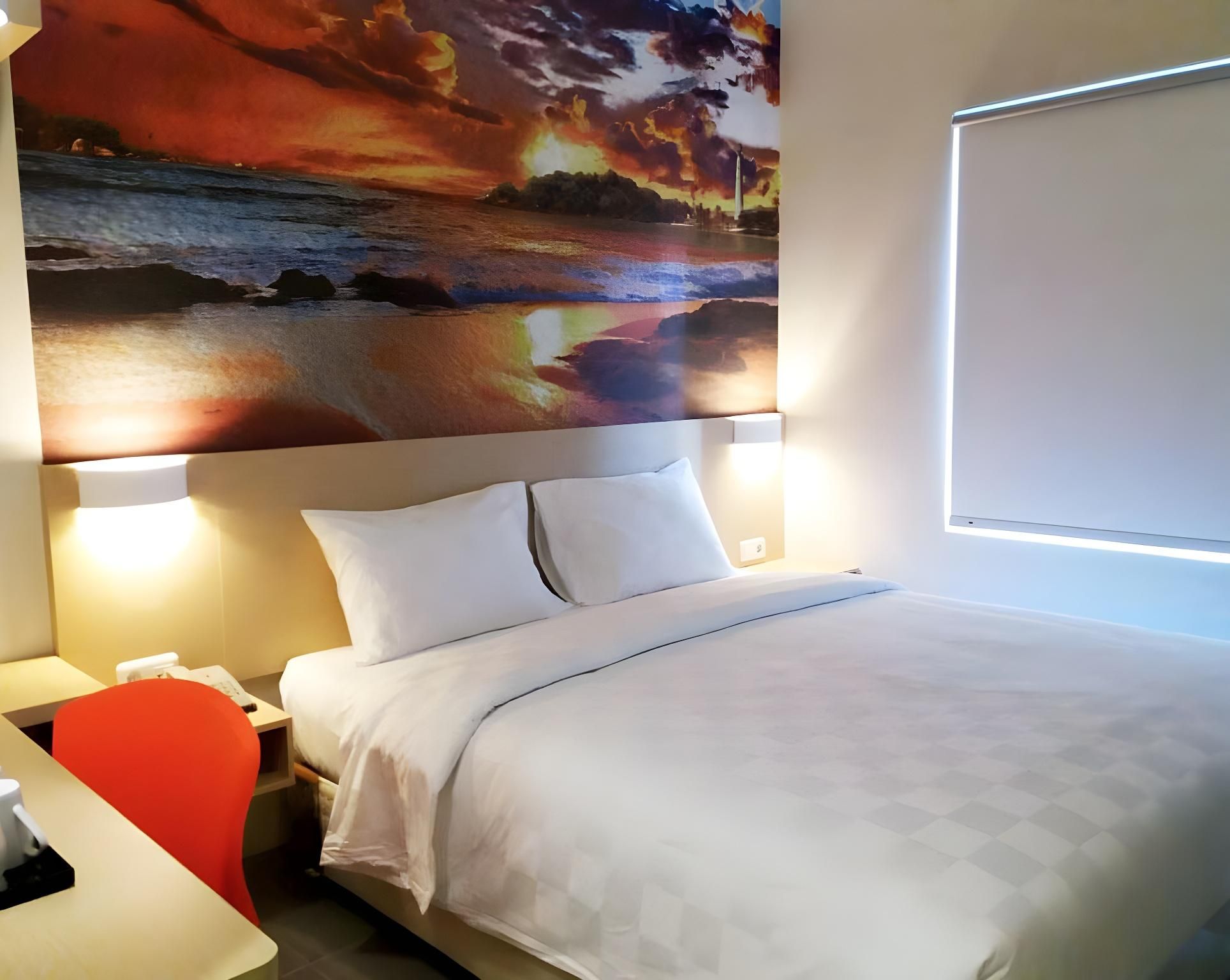 A hotel room with a bed, two bedside lamps, a desk with a chair, and a large wall painting.
