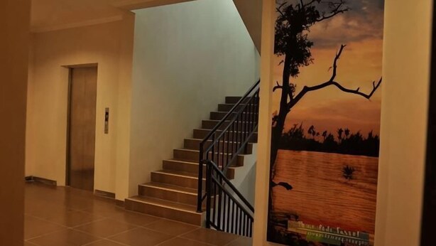 A staircase with a handrail, a wooden door, and a poster of a sunset scene. - Cordela Hotel Pangkal Pinang (Pangkalpinang)