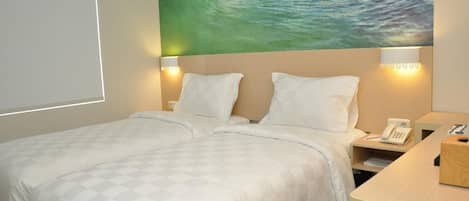 Habitación de hotel con una cama, dos lámparas de noche, una mesita de noche con un teléfono y un cuadro de una ola en la pared.