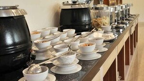 A buffet setup with multiple bowls of food and black pots on a counter. - Cordela Hotel Pangkal Pinang (Pangkalpinang)