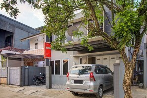 Um prédio residencial com antena parabólica, um carro estacionado e uma motocicleta.