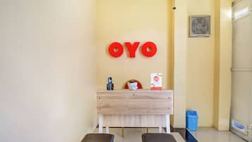 A reception area with a wooden desk, a phone, a small potted plant, and a trash bin.