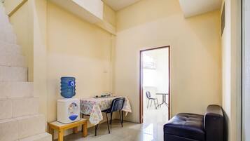 A small, well-lit room with a table, chairs, a water dispenser, and a sofa.
