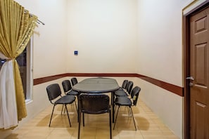 A room with a round table and eight chairs, a door, and a window with curtains. - OYO 3148 Sofia Homestay Syariah (Dramaga)