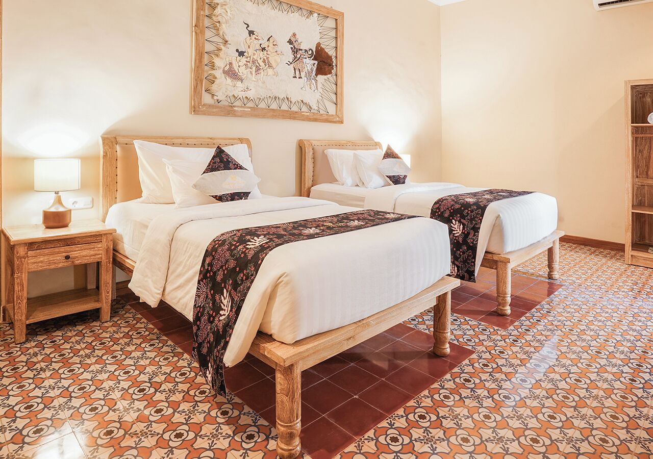 A room with two beds, a wooden headboard, a patterned floor, and a wall-mounted artwork.
