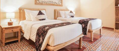 A room with two beds, a wooden headboard, a patterned floor, and a wall-mounted artwork.