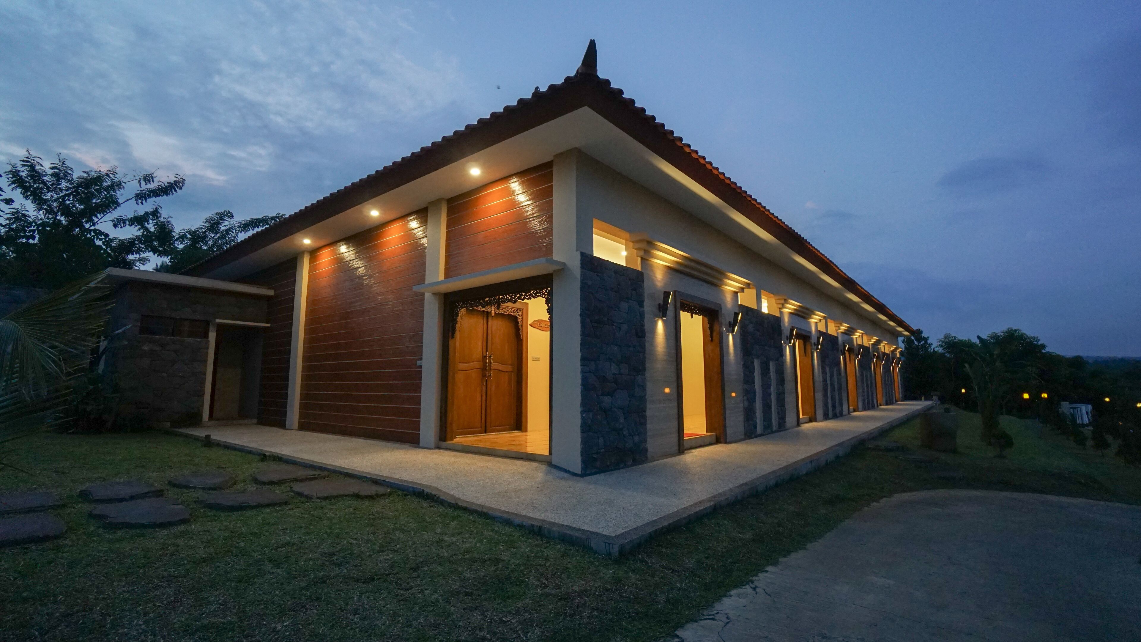 A modern house with a tiled roof, a stone facade, and a well-lit entrance.