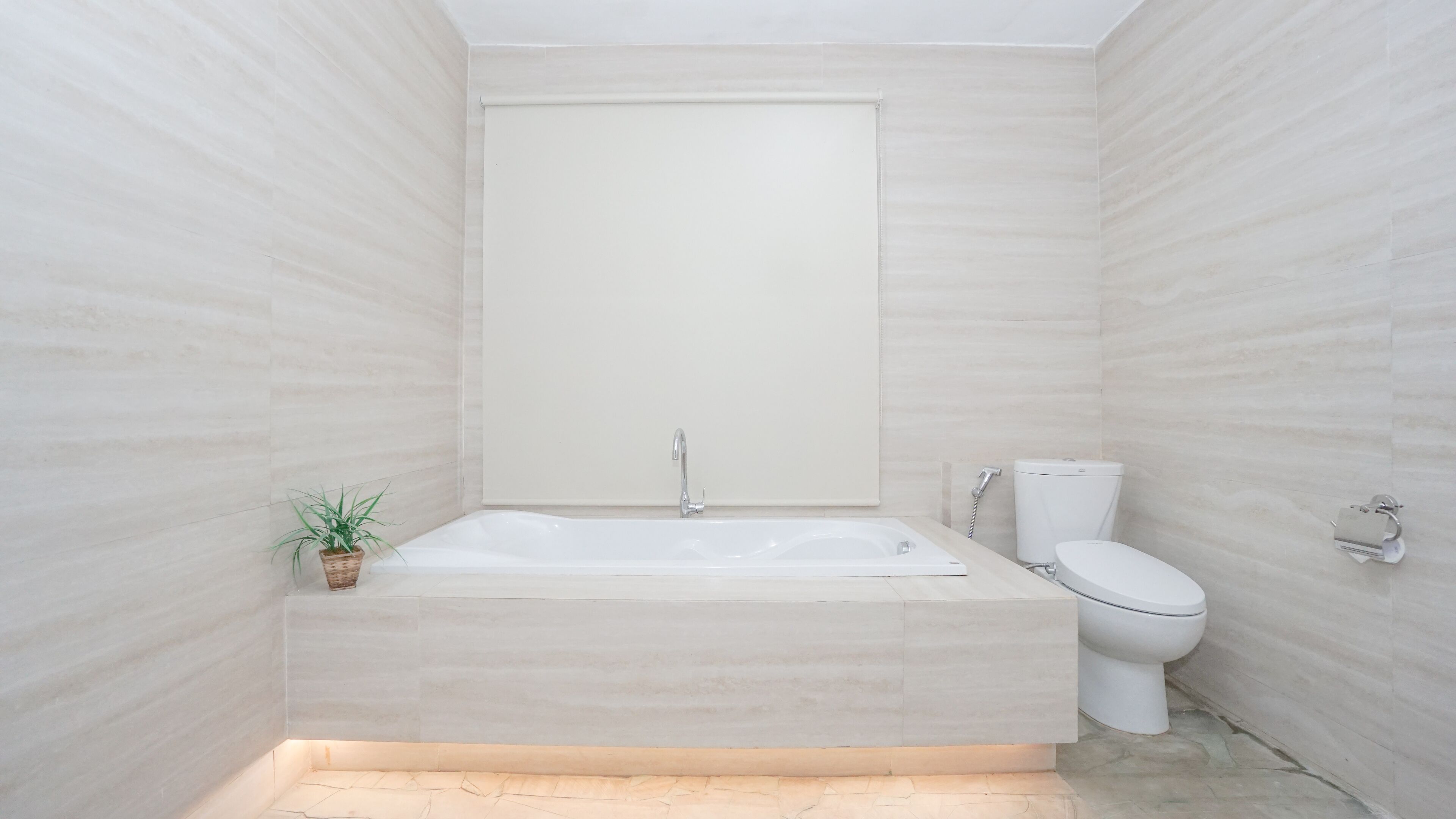 A modern bathroom with a freestanding bathtub, a toilet, and a small potted plant.