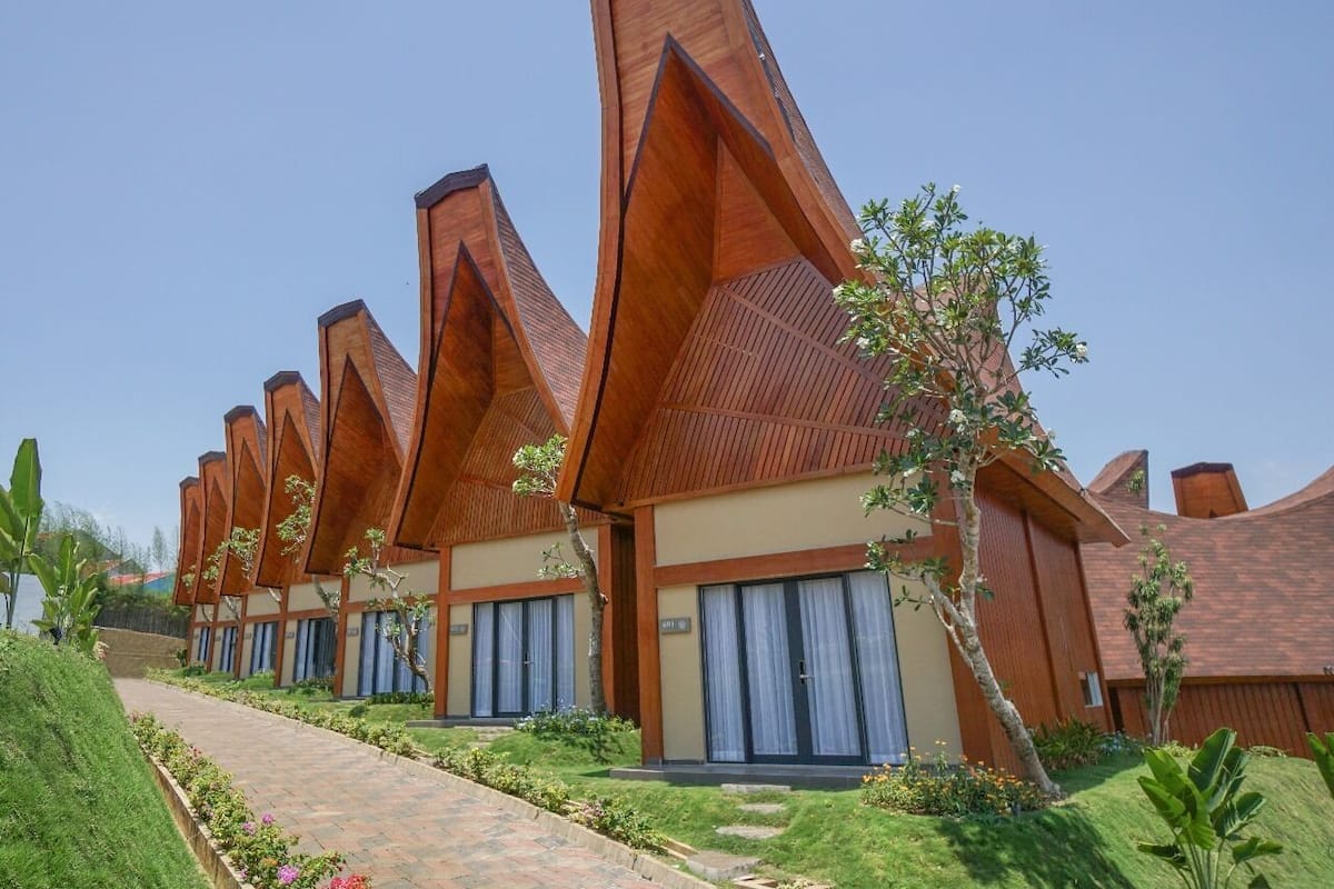 Una hilera de edificios modernos con techos de madera y amplias ventanas, con un sendero que lleva a la entrada.