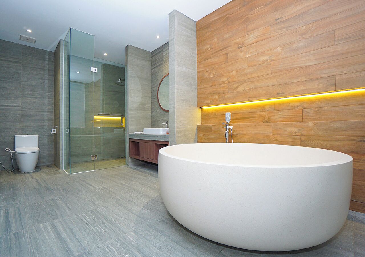 Ein modernes Badezimmer mit einer großzügigen, freistehenden Badewanne, einer Duschkabine aus Glas und einer Wand als Holzakzent.