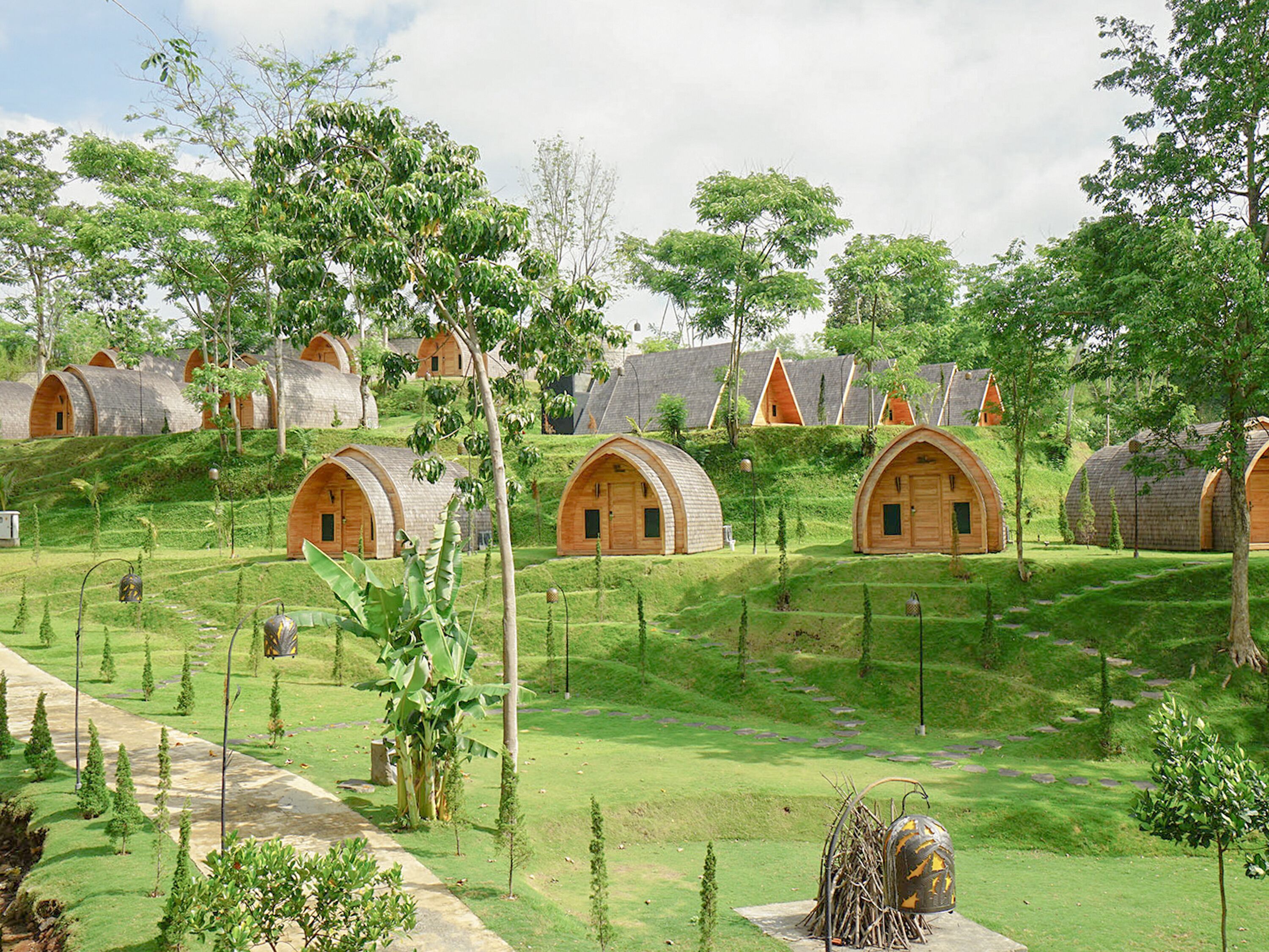 A series of dome-shaped wooden cabins arranged on a grassy hillside with a clear sky above.