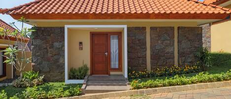 Una casa con techo de tejas, paredes de piedra, puerta de madera y entrada pavimentada.