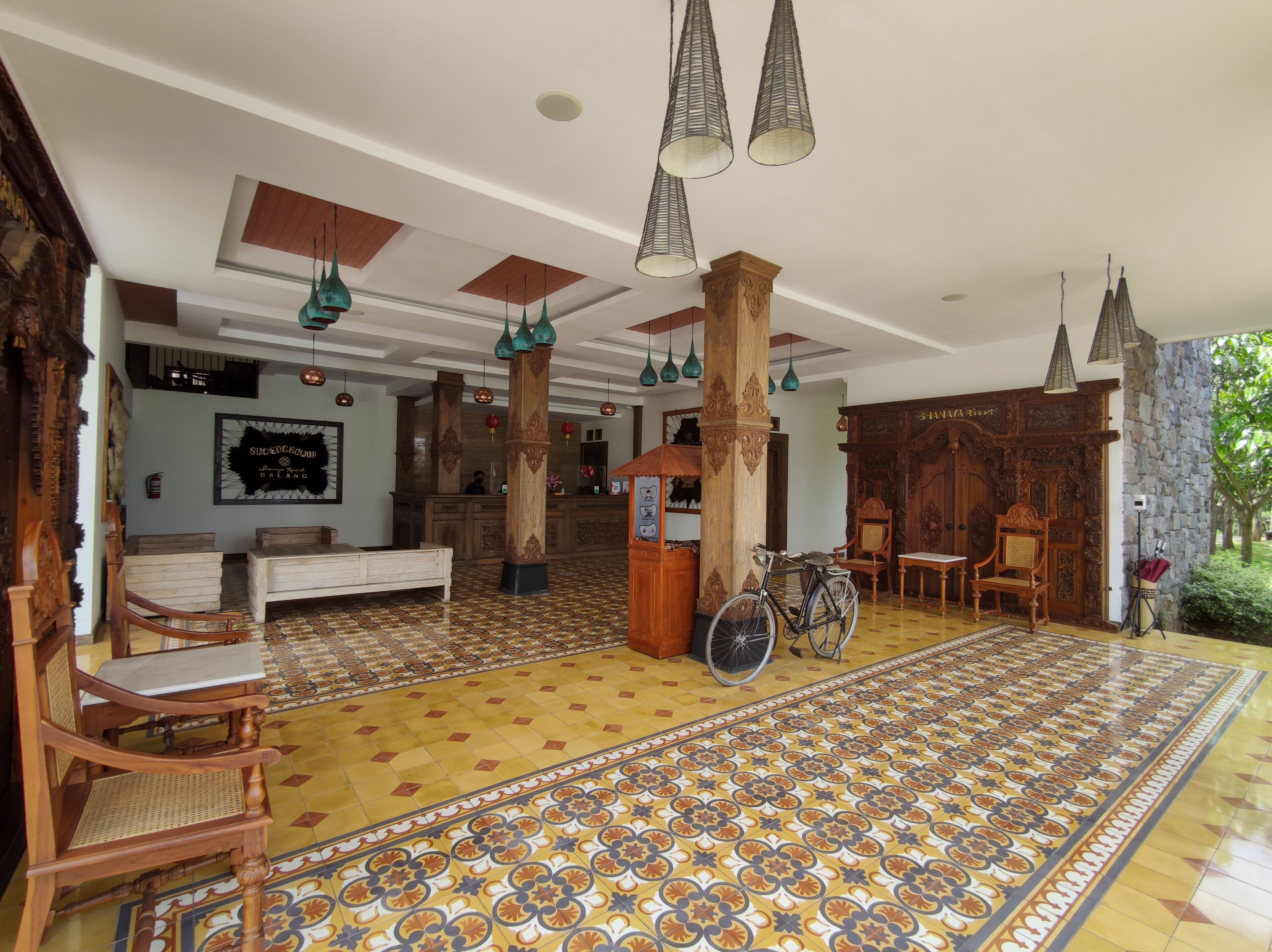 A lobby with patterned flooring, wooden furniture, and hanging lights.