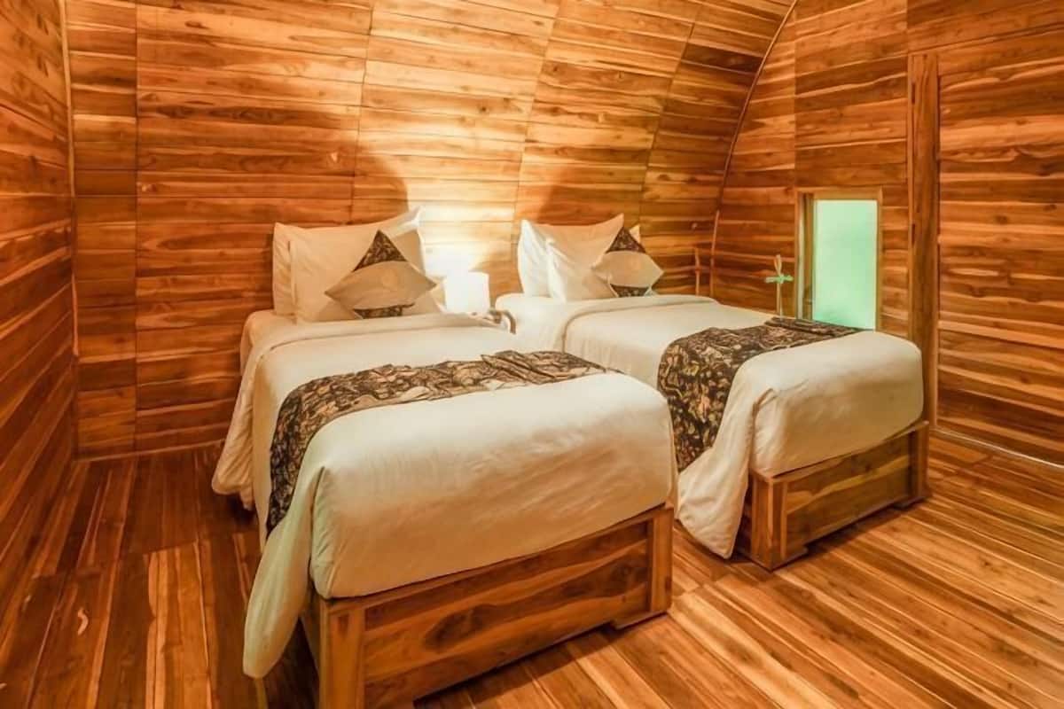 Una habitación de cabaña de madera con dos camas, una ventana y una puerta.