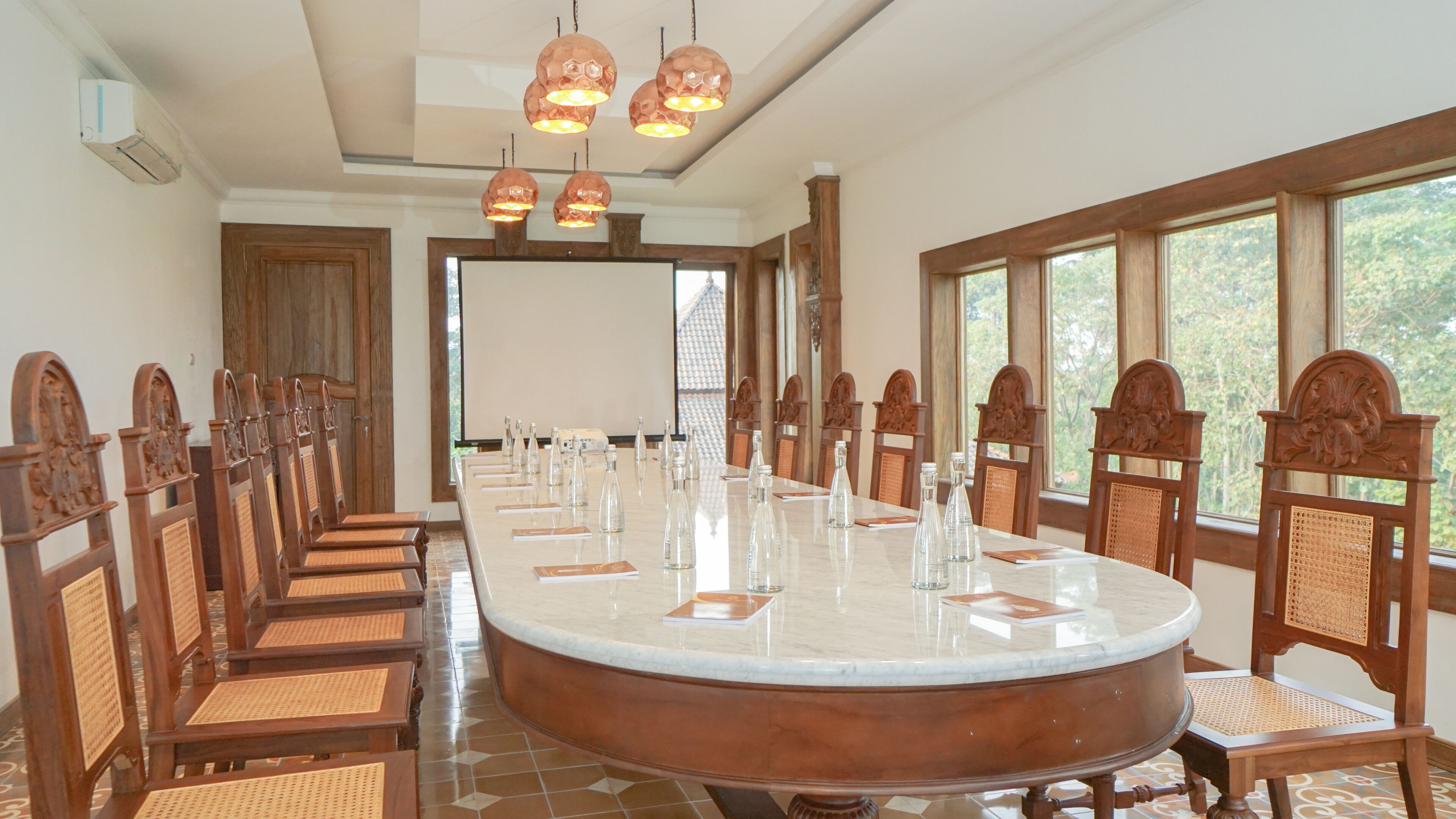 A conference room with a long table, wooden chairs, and a large window.