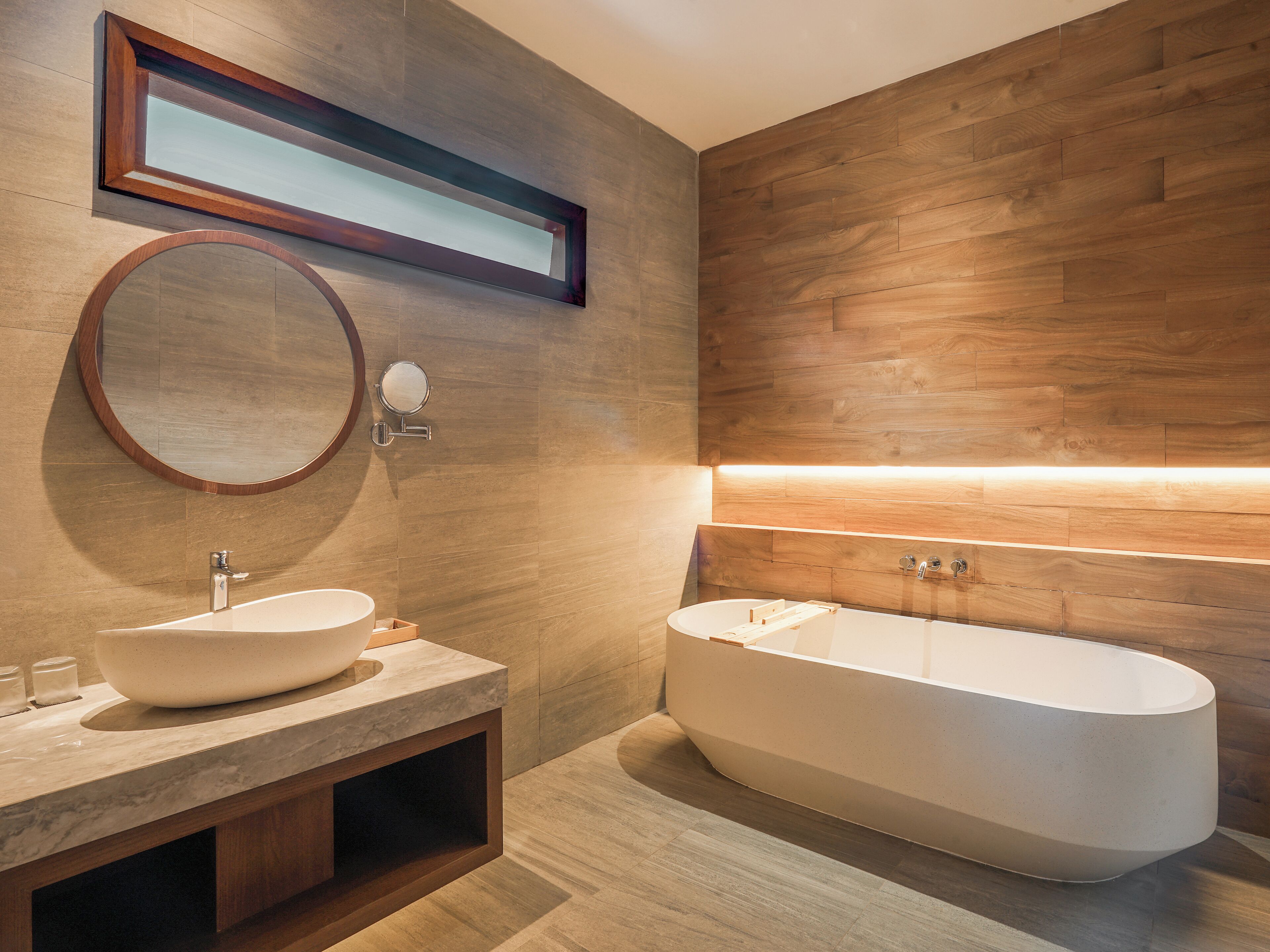 Une salle de bain moderne avec une baignoire sur pieds, un miroir rond et un lavabo en marbre.