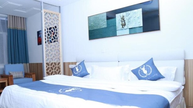 Una habitació d'hotel amb un llit, una cadira, un panell decoratiu i un quadre a la paret.