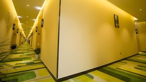 Un largo pasillo bien iluminado con suelo de estampado verde y amarillo, que conduce a varias habitaciones.