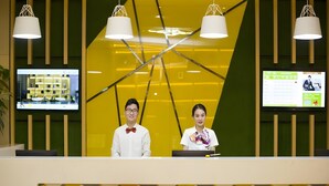 Una recepción con dos empleados, diseño interior moderno y una pantalla digital.
