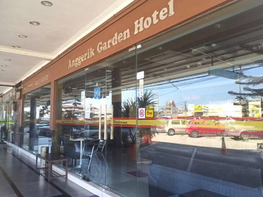 The exterior of Anggerik Garden Hotel with a clear view of the entrance, a glass facade, and a parking area visible through the windows.