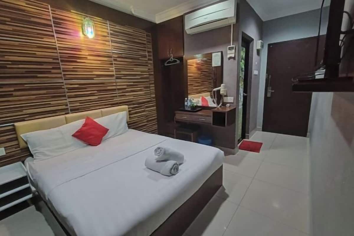 Camera d'albergo con un letto, un pannello parete in legno, uno specchio, una scrivania e un condizionatore d'aria.