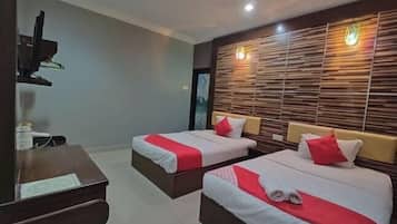 A hotel room with two beds, a desk, and a television.