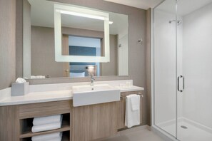 A modern bathroom with a large mirror, two sinks, and a glass shower enclosure.