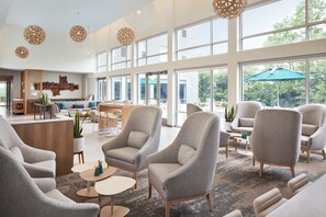 A spacious lobby with high ceilings, large windows, and modern furniture.