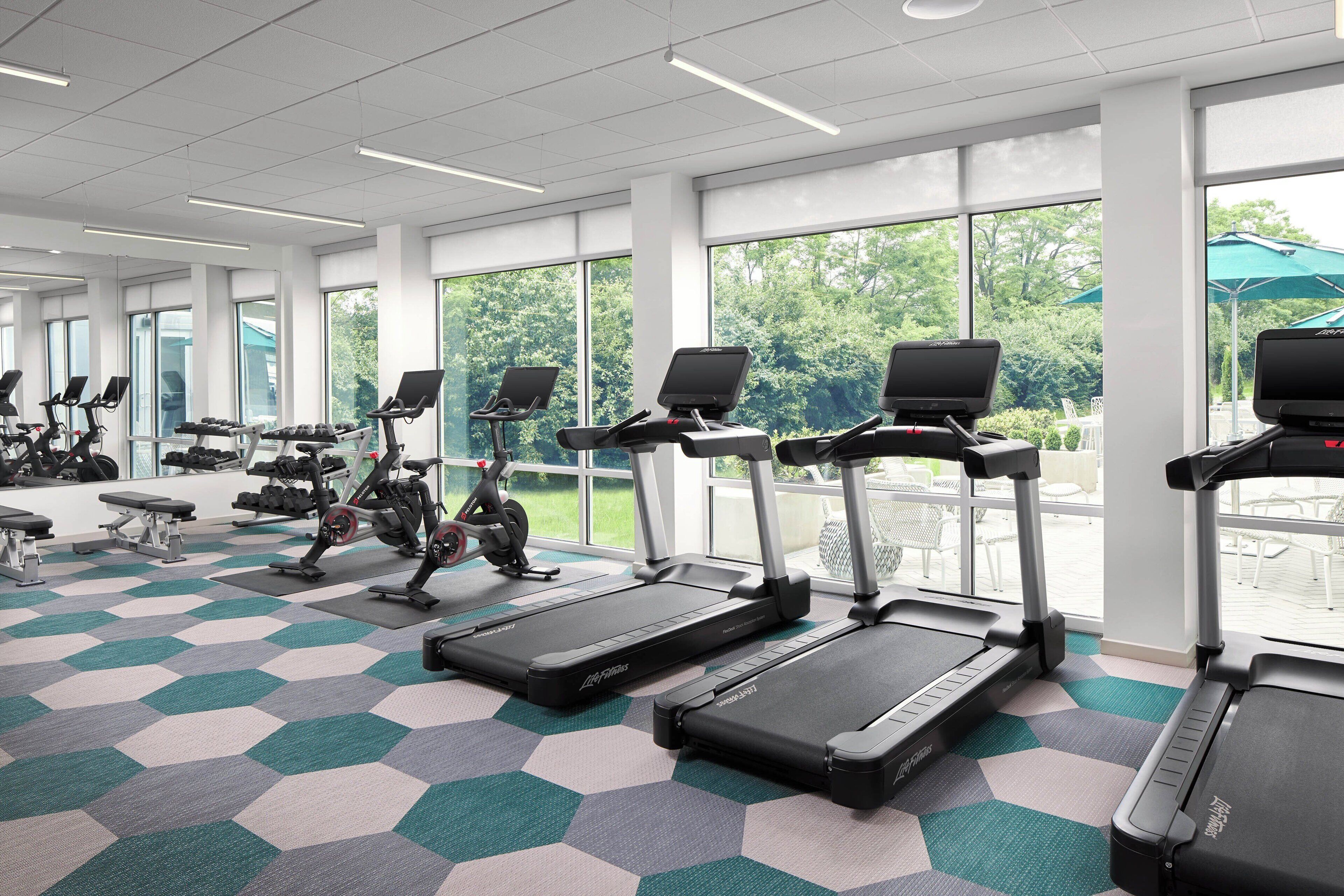 Une salle de sport équipée de tapis de course, de vélos d’exercice et de bancs.