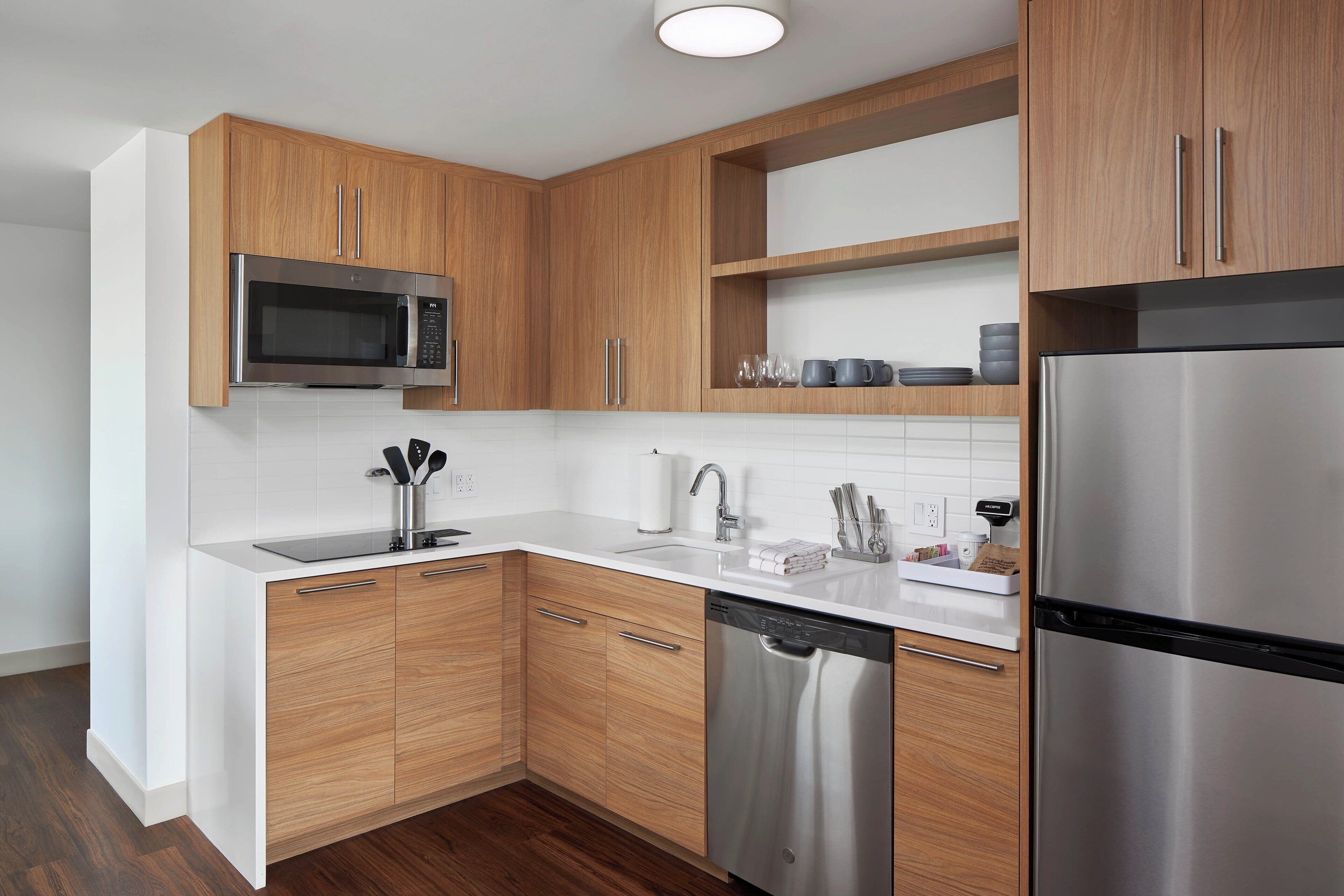 Une cuisine moderne avec des meubles en bois, des appareils en acier inoxydable et un plan de travail blanc.