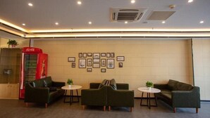 A lobby with a red telephone booth, framed pictures on the wall, and three green sofas with small tables. - Greentree Inn Dezhou Xiajin County Debai Trade Market Express Hotel (Dezhou)