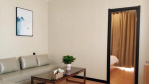 A modern living room with a sofa, a coffee table, a potted plant, and a framed picture on the wall. - Greentree Inn Dezhou Xiajin County Debai Trade Market Express Hotel (Dezhou)