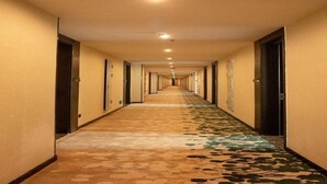 A long, narrow hotel corridor with doors on both sides, a patterned carpet, and recessed lighting on the ceiling. - Greentree Inn Dezhou Xiajin County Debai Trade Market Express Hotel (Dezhou)