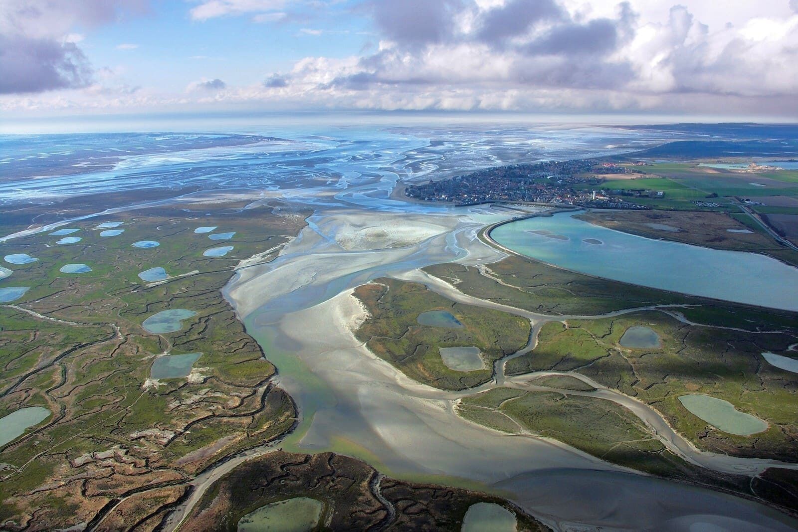An aerial view of a coastal area with multiple water bodies and a town in the distance.
