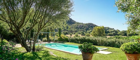 Une piscine entourée d’une végétation luxuriante, avec une chaîne de montagnes en toile de fond.