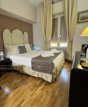 A neatly arranged bedroom with a bed, curtains, a bedside table, and a lamp. - Maison delle Naiadi (Rome)