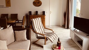 A living room with a sofa, armchair, dining table, and TV. - Beautiful and spacious holiday home (Bad Harzburg)